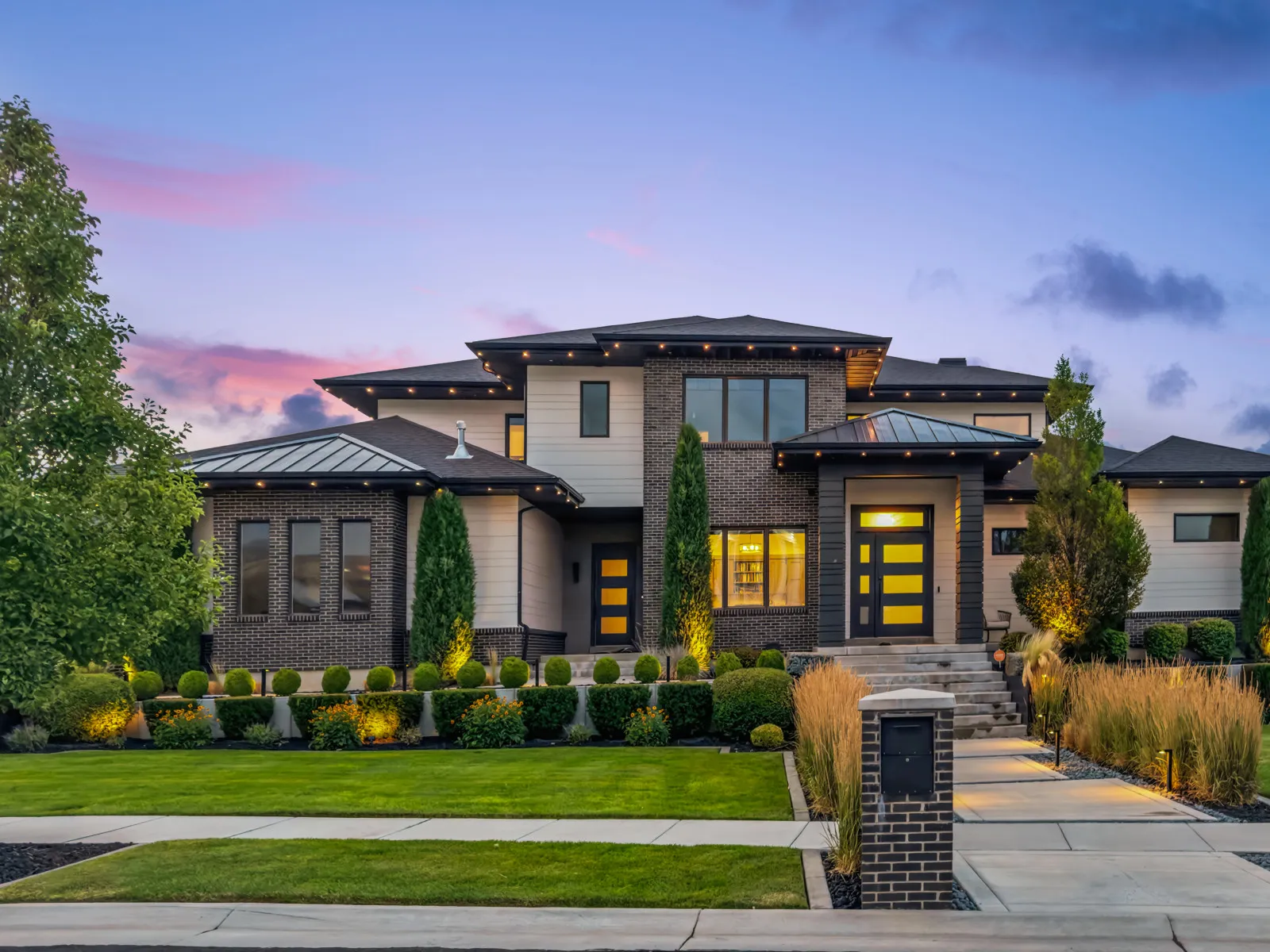 Manicured lawn with boxwood sphere topiaries flanking walkway and landscape accent lighting.
